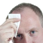 A businessman wiping his sweat from his forehead